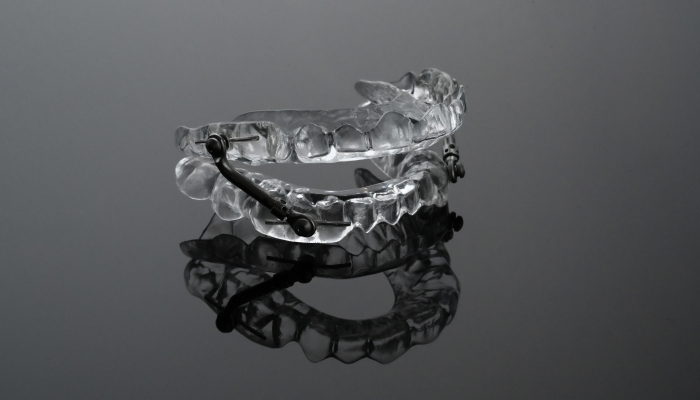 A mandibular advancement device, used to treat obstructive sleep apnea and snoring, displayed against a black-grayish background.