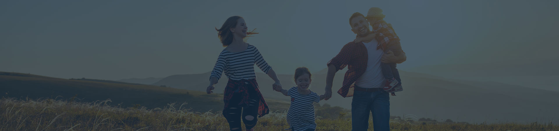 A family of four, consisting the father, the mother and two children, smiling and holding each other, symbolizing a wholesome, family-oriented approach to holistic dentistry.